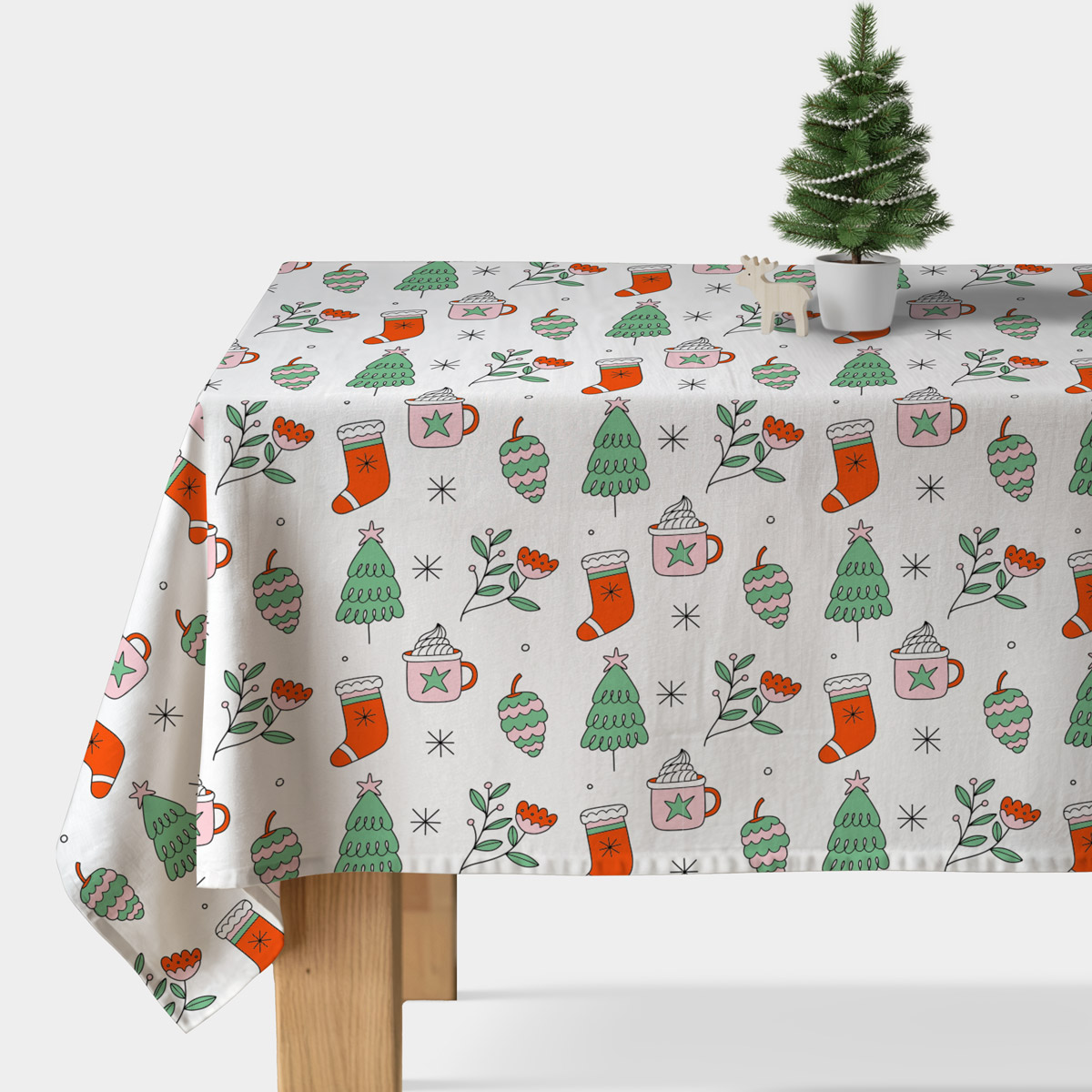 obrus biały z motywem choinek i kubków na stole w jasnym wnętrzu