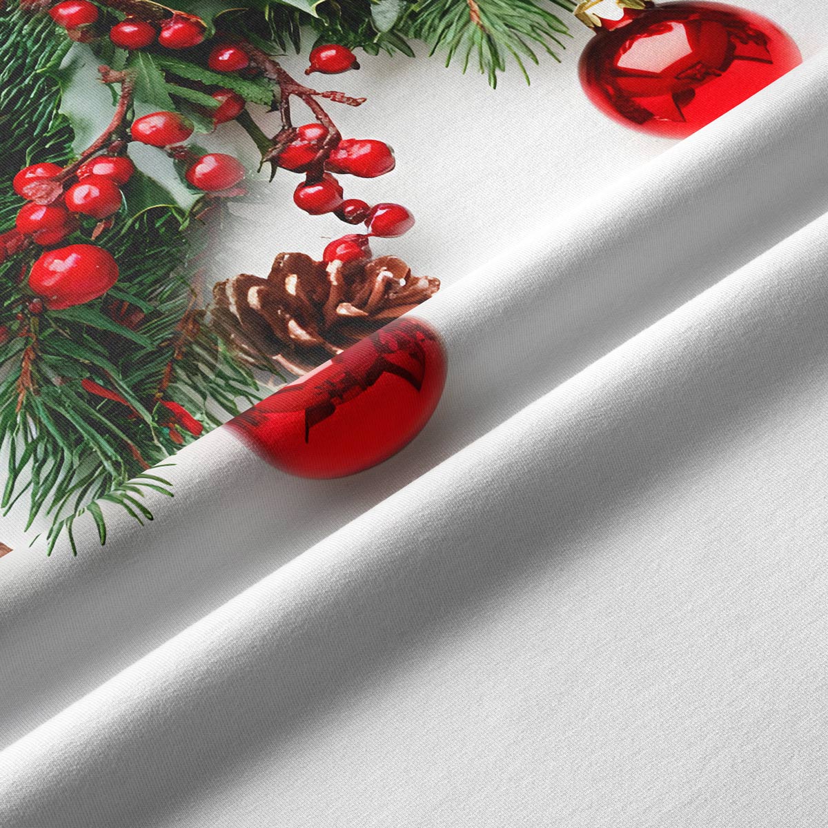 Zbliżenie na tkaninę bieżnika świątecznego z nadrukiem świerku, szyszek i czerwonych bombek.