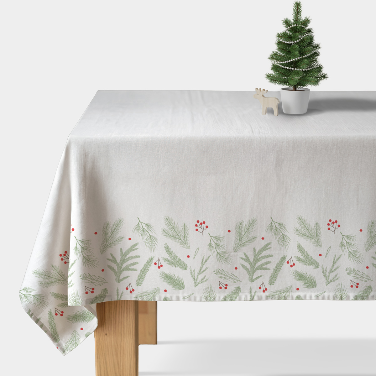 biały obrus świąteczny z zielonymi gałązkami i czerwonymi jagodami