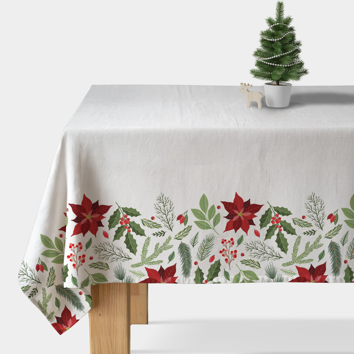 biały obrus świąteczny z czerwonymi gwiazdami betlejemskimi i zielonymi gałązkami