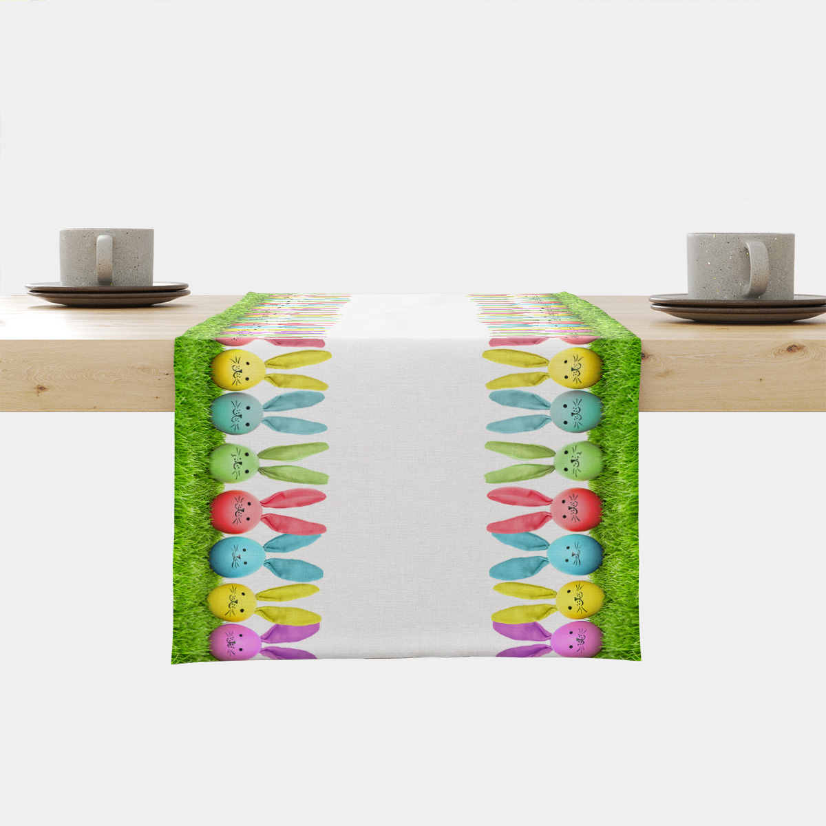 Bieżnik rozłożony na drewnianym stole z bordiurą kolorowych pastelowych zajączków i trawiastym brzegiem