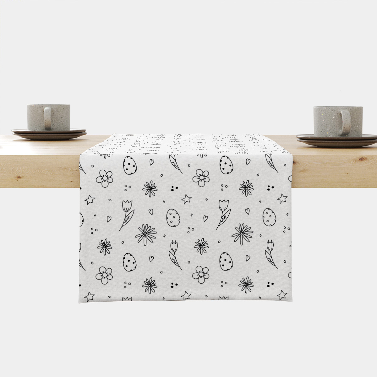 Bieżnik rozłożony na jasnym stole z widocznym frontowym ujęciem wzoru pisanek i kwiatów