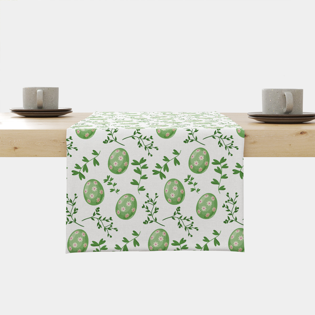 Bieżnik na stole z wzorem zielonych pisanek i zielonych gałązek na jasnym tle
