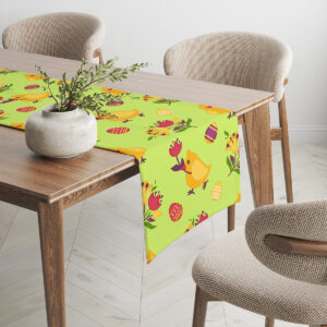 Bieżnik rozłożony na stole z widocznym wzorem kurczaczków i kolorowych jajek przy krawędzi