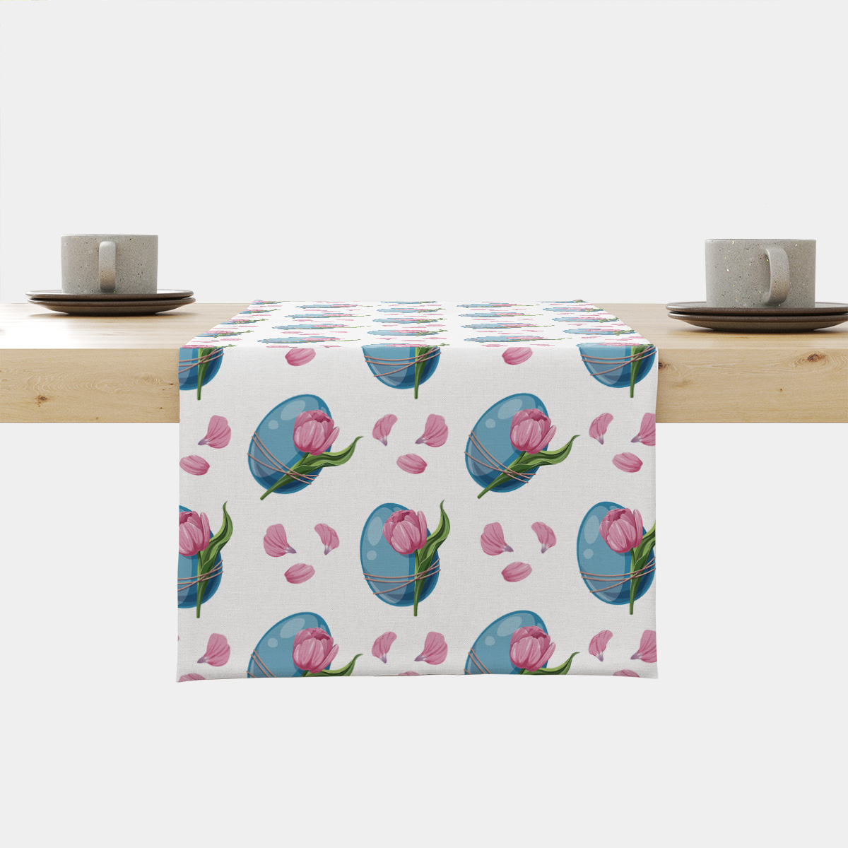 Bieżnik rozłożony na stole z wzorem niebieskich pisanek i różowych tulipanów