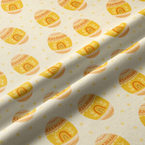 Zbliżenie tkaniny pokazujące powtarzające się żółte pisanki i drobne kropki oraz fakturę materiału