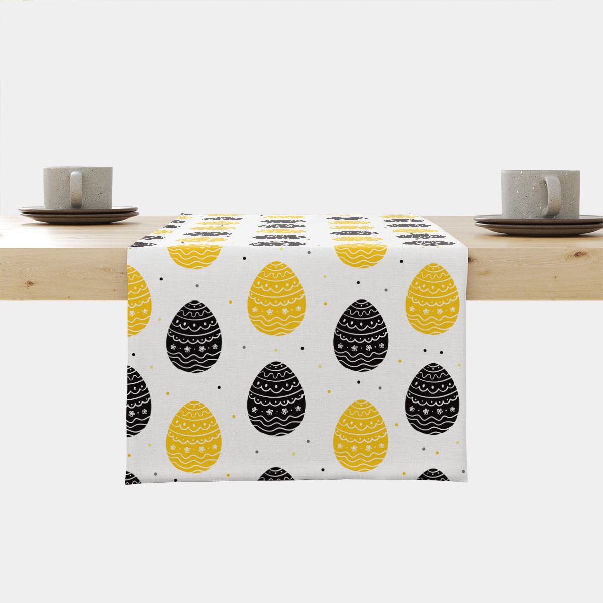 Bieżnik z motywem żółtych i czarnych pisanek ułożony na stole, widok frontalny