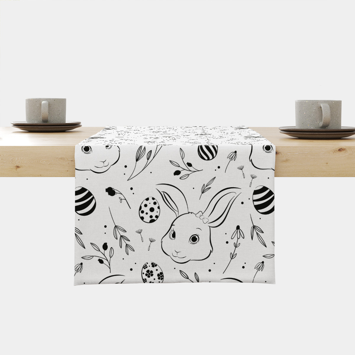 Bieżnik z czarno-białym wzorem wielkanocnym z króliczkami i pisankami ułożony na drewnianym stole