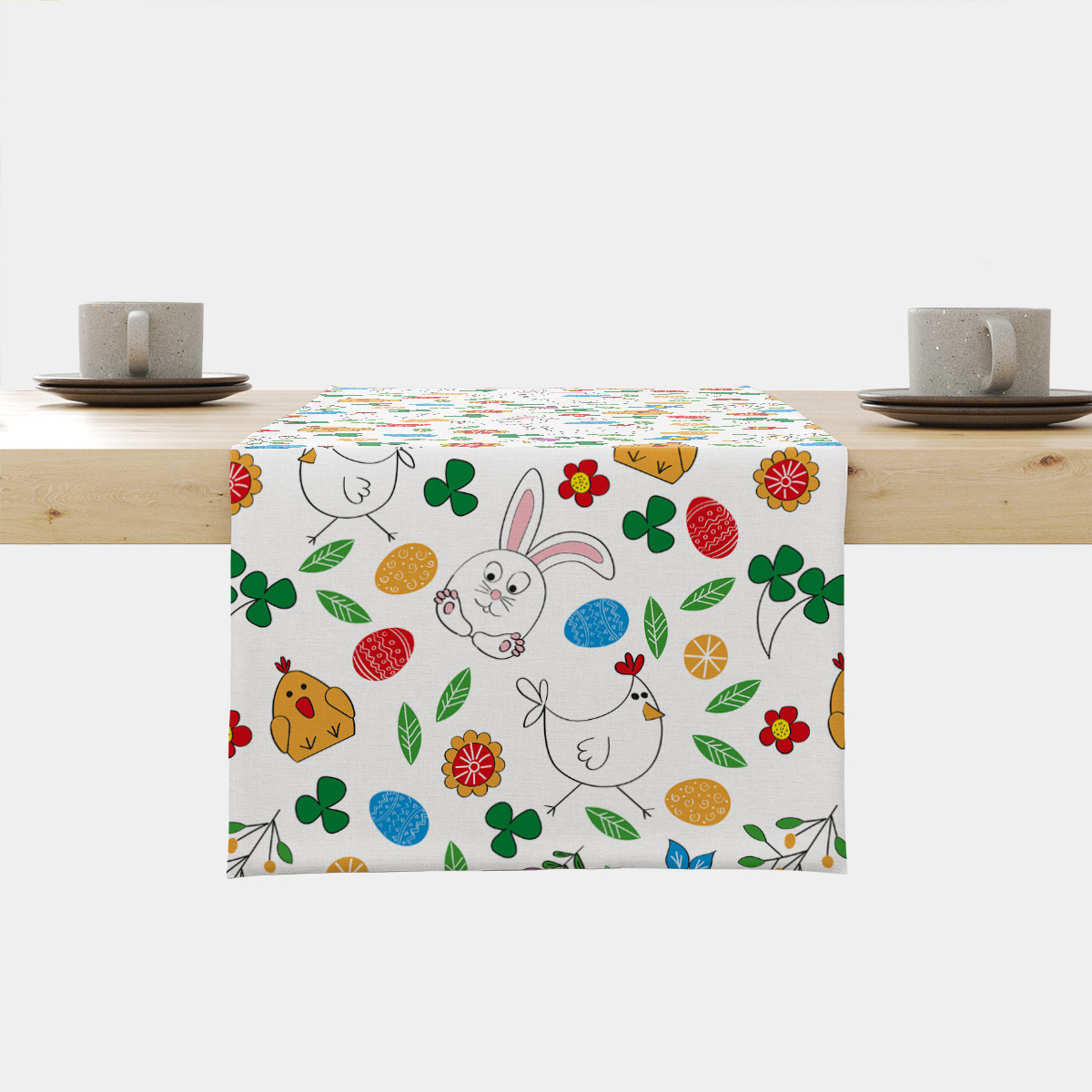 Bieżnik z wielkanocnym wzorem króliczków, kurczaczków i pisanek na białym tle ułożony na blacie
