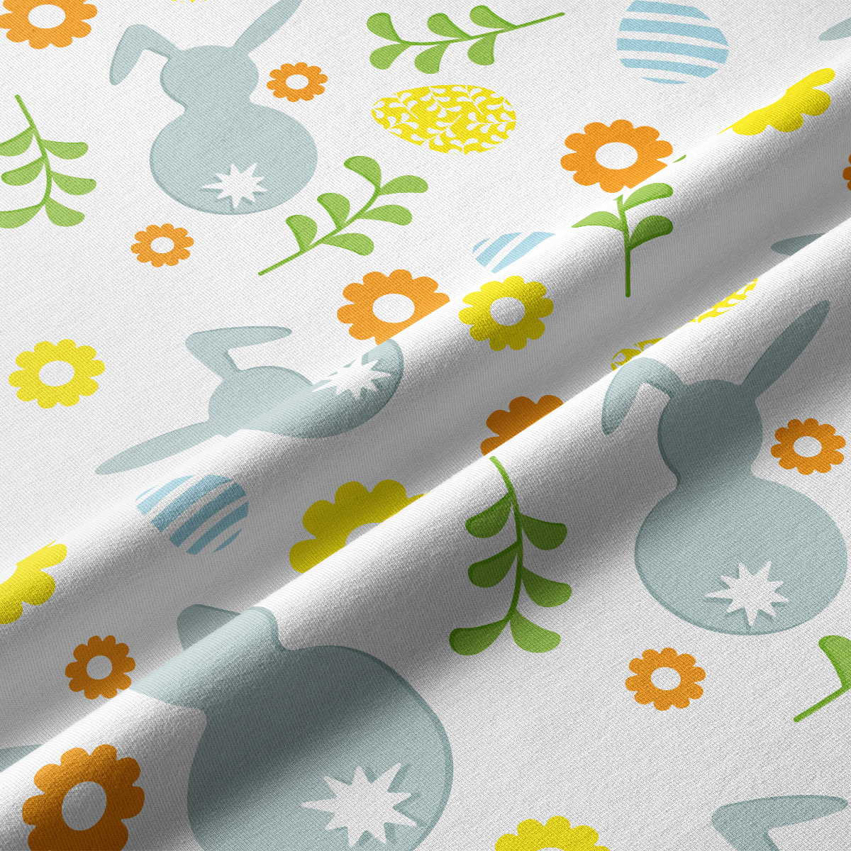 Zbliżenie tkaniny pokazujące detal wzoru z zajączkami, pisankami i kwiatami oraz delikatną fakturę materiału