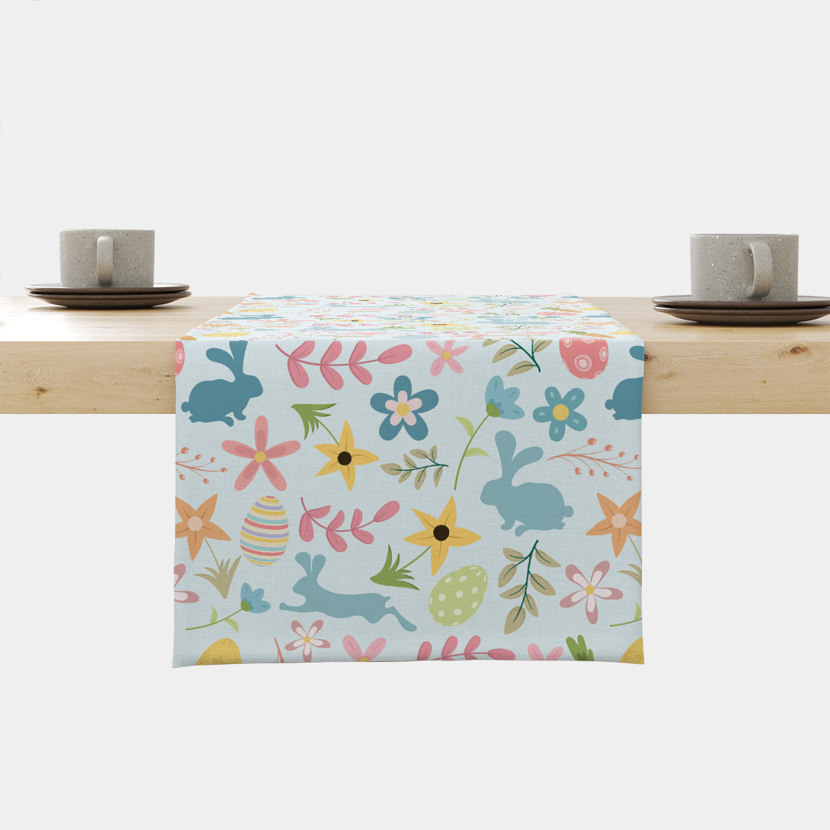 Bieżnik rozłożony na drewnianym stole z motywem wielkanocnych zajączków i pisanek w pastelowych barwach