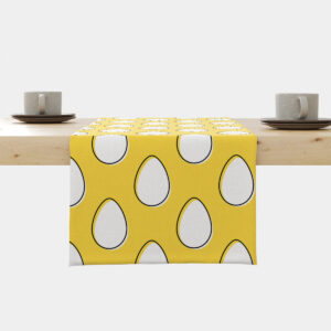 Bieżnik na stole w żółtym tle z białymi pisankami ułożony na drewnianym blacie z filiżankami