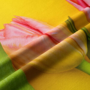 Zbliżenie tkaniny z nadrukiem różowego tulipana i widoczną strukturą materiału