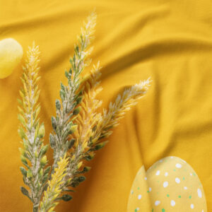 Zbliżenie na nadruk kłosów i pisanki na żółtej tkaninie