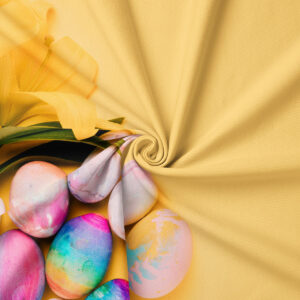 Zbliżenie na fakturę tkaniny i akwarelowe pisanki z fragmentem żółtego tulipana