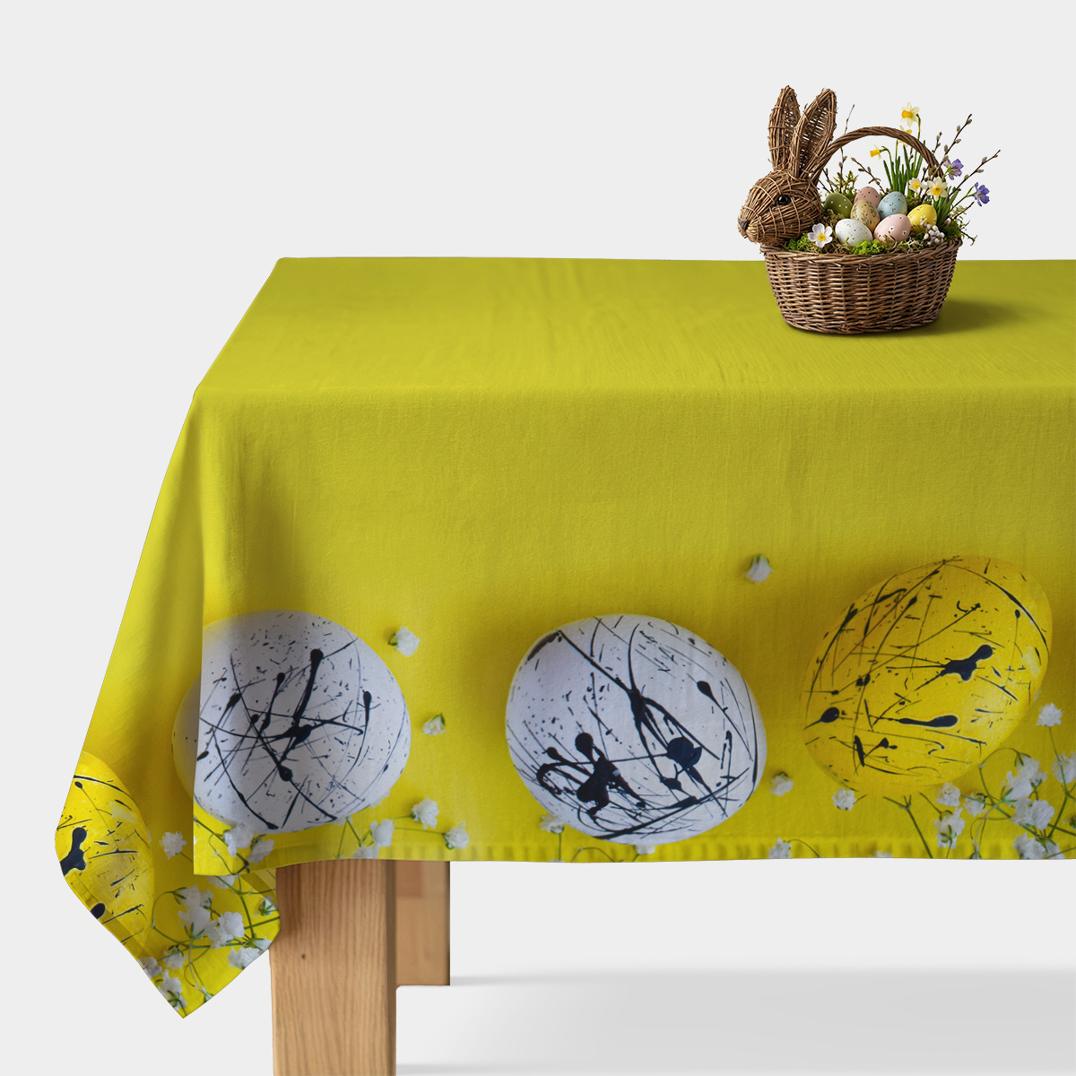 obrus w limonkowym odcieniu z dekoracyjnym pasem malowanych pisanek i koszykiem wielkanocnym na rogu stołu