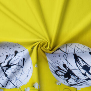 zbliżenie na tkaninę i dwa białe pisanki z czarnymi, abstrakcyjnymi plamami na limonkowym tle