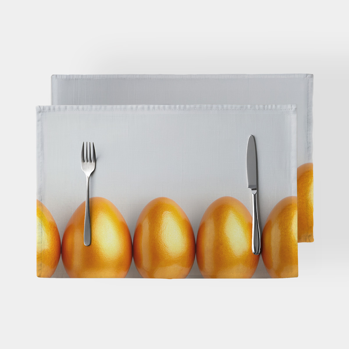 Podkładka z motywem złotych pisanek ułożonych w rzędzie na jasnym tle, widok z góry