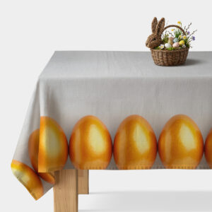 Obrus na stole z jasnoszarym tłem i pasem połyskujących złotych pisanek przy krawędzi