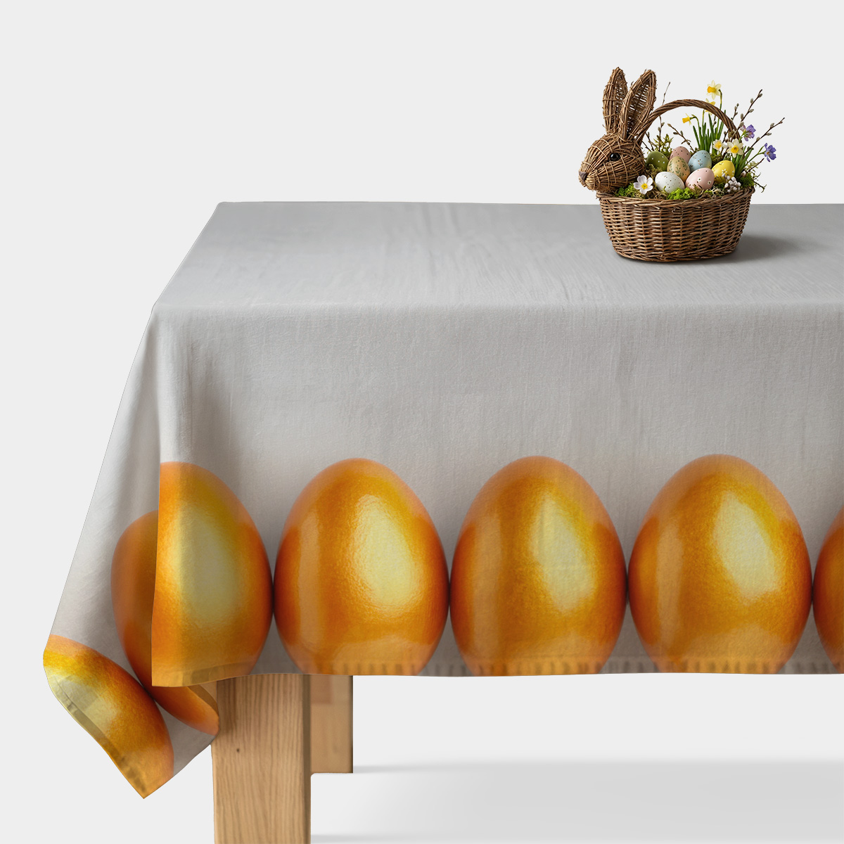 Obrus na stole z jasnoszarym tłem i pasem połyskujących złotych pisanek przy krawędzi