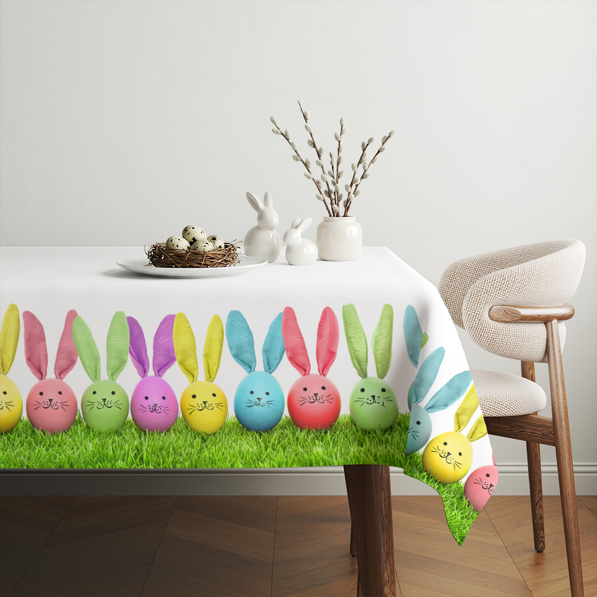 Aranżacja stołu z wazą, gniazdem z jajkami i dekoracjami na obrusie z pisankami