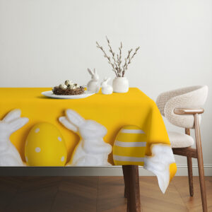 Aranżacja stołu z gniazdem jajek, ceramicznymi zajączkami i gałązkami bazi na żółtym obrusie
