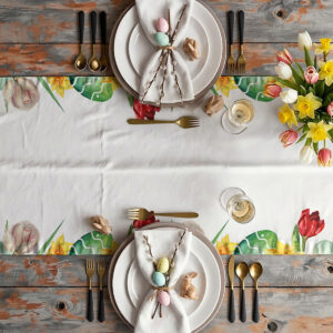 Aranżacja stołu z talerzami, serwetkami i bukietem tulipanów na bieżniku z kwiatowym brzegiem i pisankami