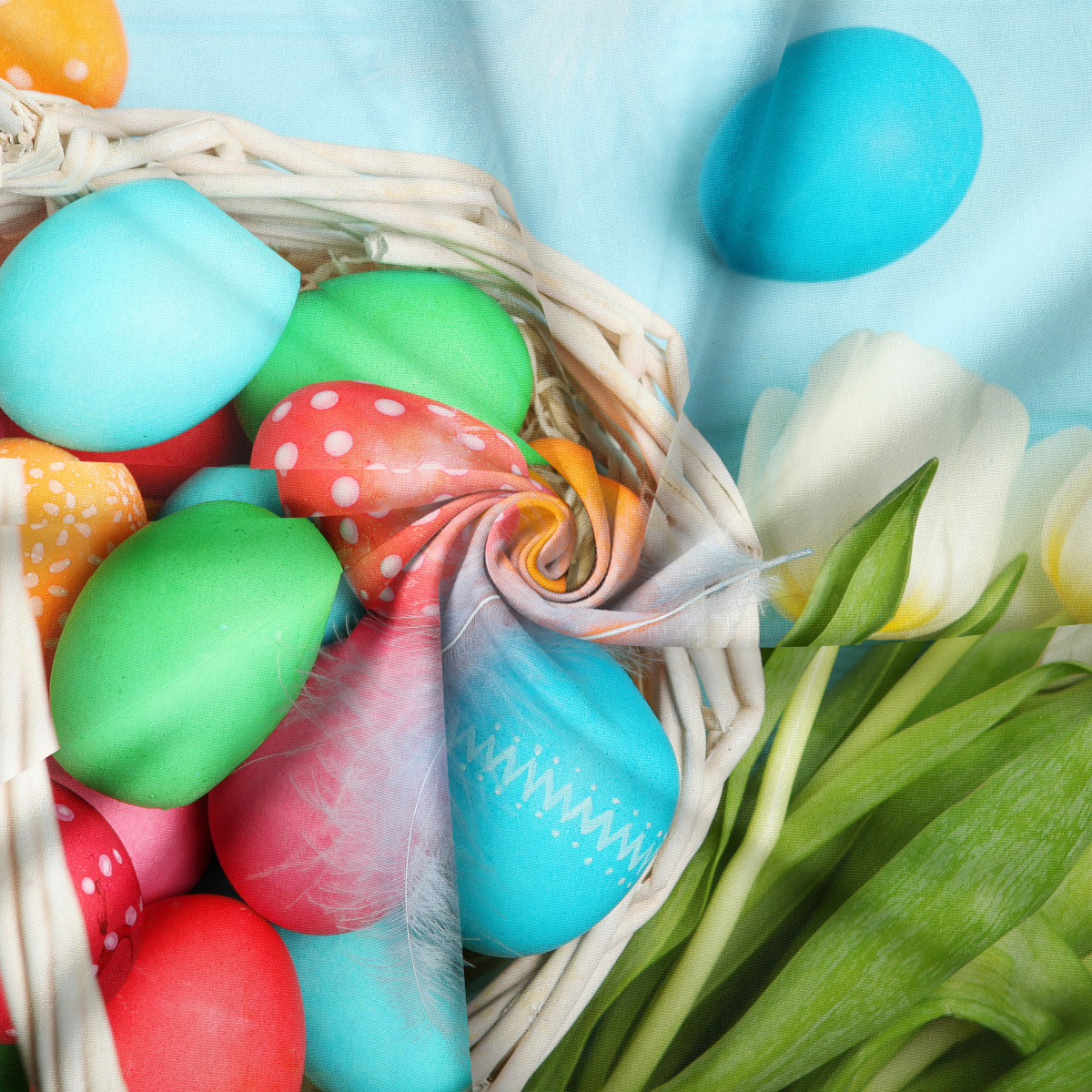 Zbliżenie na malowane jajka w wiklinowym koszyku z delikatnym piórkiem