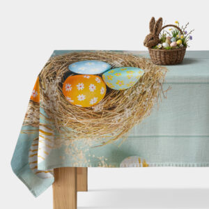 główny widok obrus z gniazdem i trzema kolorowymi pisankami rozłożony na stole