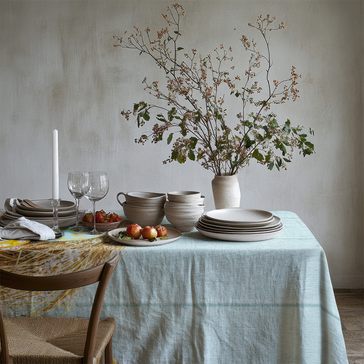 detal stołu z obrusm, talerzami i naturalnymi ozdobami wokół wzoru gniazda