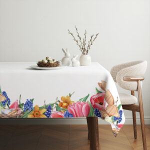 Aranżacja stołu z obruszem, białymi ceramicznymi zajączkami i wiklinowym gniazdem na środku