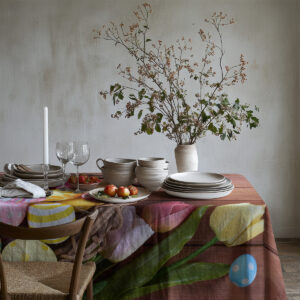 detal brzegu obrusa z tulipanami i pojedynczym niebieskim jajkiem na tle drewnianej tekstury