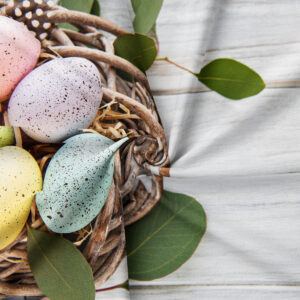 Zbliżenie na złożony obrus pokazujące nadruk pisanek, wikliny i liści