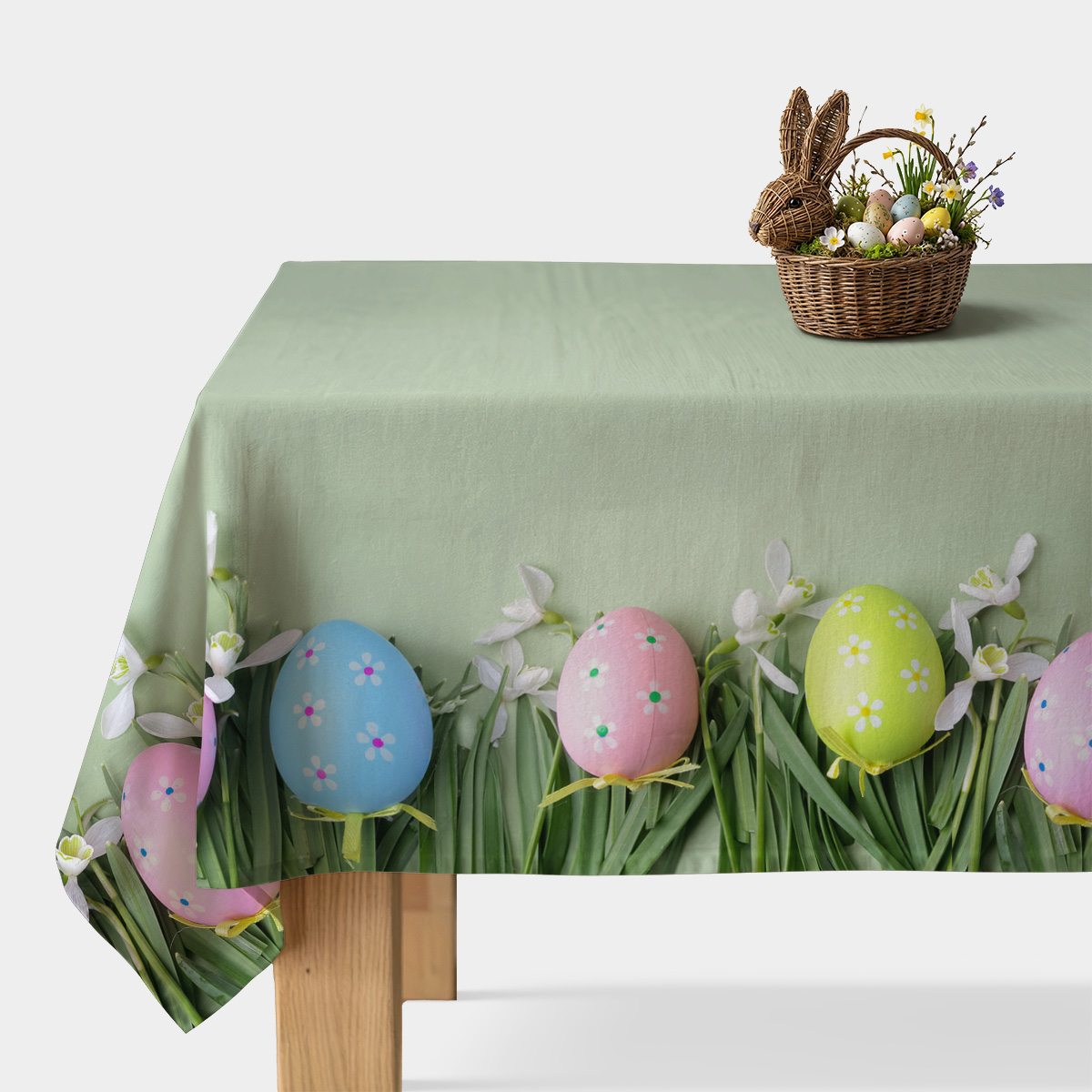 Obrus z miętowym tłem ozdobiony kolorowymi jajkami i zieloną trawą