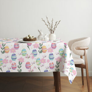 Aranżacja stołu z obrusem, ceramicznymi ozdobami w kształcie zajączków i gniazdkiem z jajkami