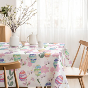 Jasna jadalnia z obrusem ozdobionym pisankami i różowymi kwiatami oraz wazonem z gałązkami