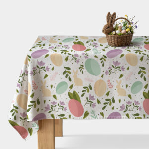 Stół nakryty obrusem z pastelowymi pisankami i zajączkami oraz wiklinowy koszyk z dekoracyjnymi jajkami