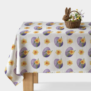 Obrus z motywem fioletowych pisanek i żonkili na stole z wiklinowym koszykiem wielkanocnym