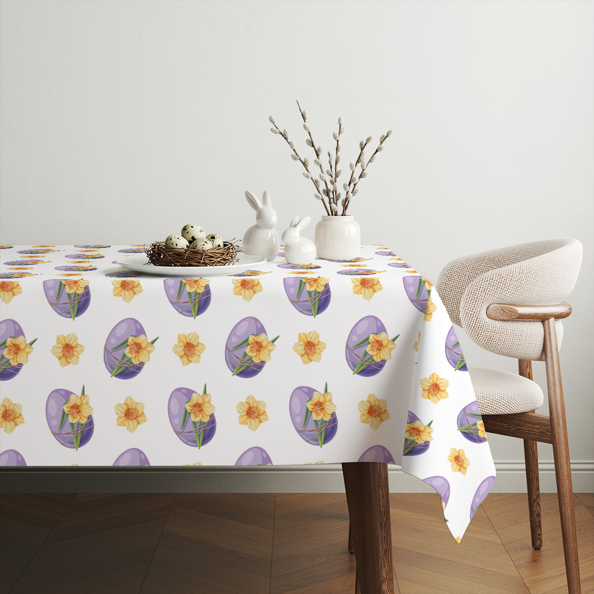 Aranżacja stołu z obrusem, ceramicznymi ozdobami i gałązkami bazie tworząca wielkanocny nastrój