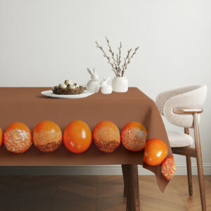 aranżacja stołu z wiklinowym koszykiem, bukszpanem i obrus z pomarańczowymi pisankami