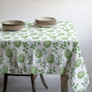 Widok stołu z nałożonymi talerzami i miskami na obrusie z motywem pisanek