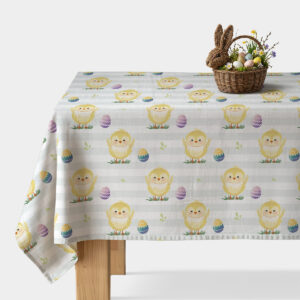 Obrus z motywem wielkanocnych kurczaczków i pisanek na stole z wiklinowym koszykiem dekoracji