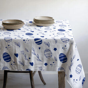 stół nakryty obrusem w drobny wzór pisanek z ułożonymi talerzami i miseczkami