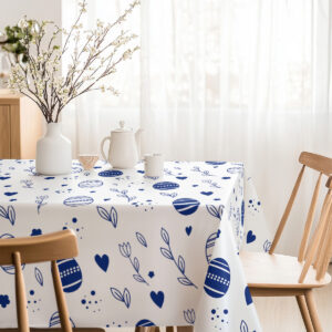 narożnik obrusa z motywem pisanek widoczny przy drewnianym krześle w jasnej jadalni