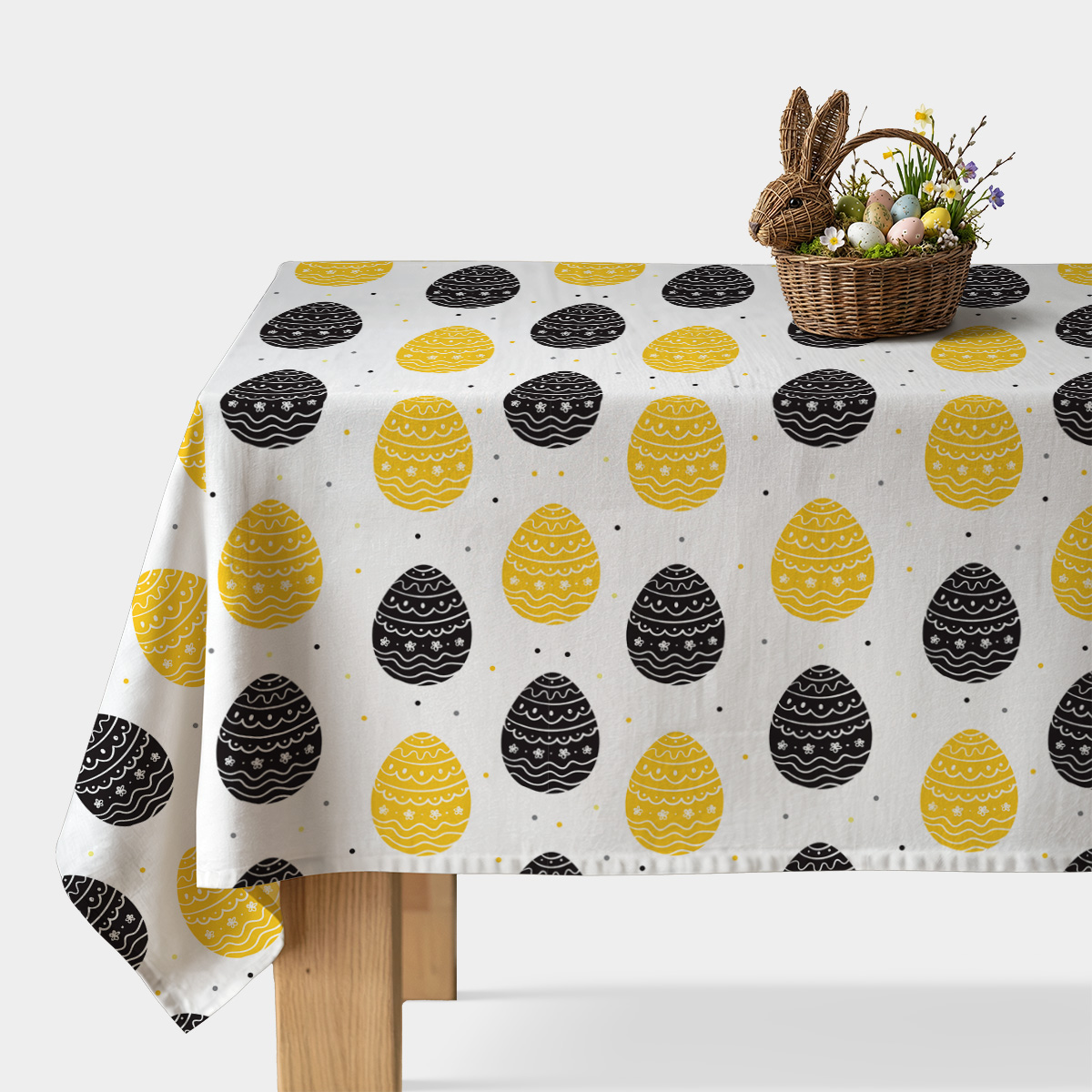 Obrus z żółtymi i czarnymi pisankami na białym tle, widok główny z koszykiem wielkanocnym