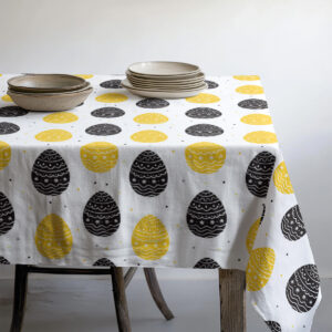 Detal krawędzi obrusu i ułożone naczynia na stole, widok boczny aranżacji