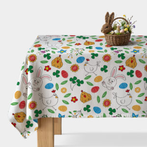 Obrus z wielkanocnym wzorem króliczków, kurczaczków i kolorowych pisanek na białym tle z wiklinowym koszykiem na rogu stołu