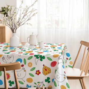 Stołowa aranżacja w jasnym wnętrzu z wesołym wielkanocnym motywem na obrusie
