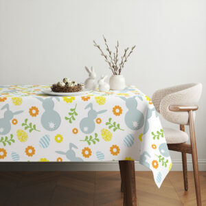 Aranżacja stołu z ceramicznymi zajączkami i gałązkami umieszczonymi na wzorzystym obrusie