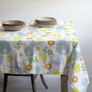 Widok stołu z talerzami i miseczkami ustawionymi na obrusie z wiosennym motywem